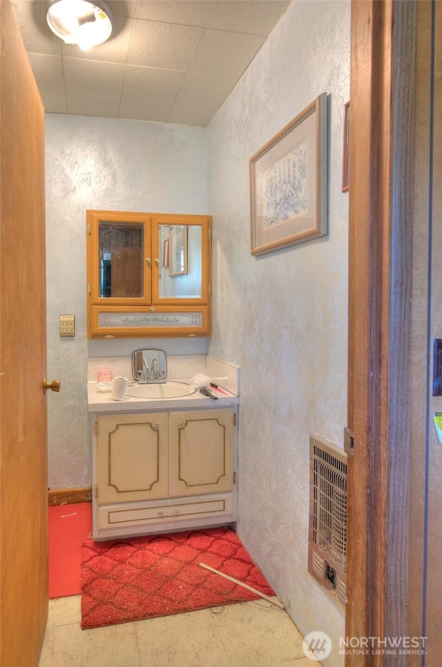 bathroom with a textured wall, vanity, and heating unit