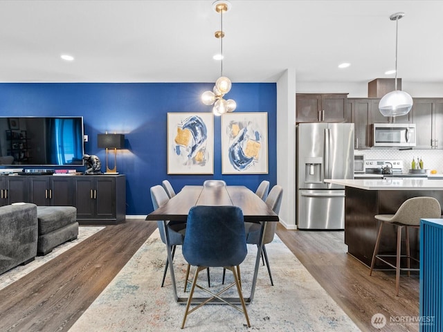 dining space featuring baseboards, a chandelier, wood finished floors, and recessed lighting