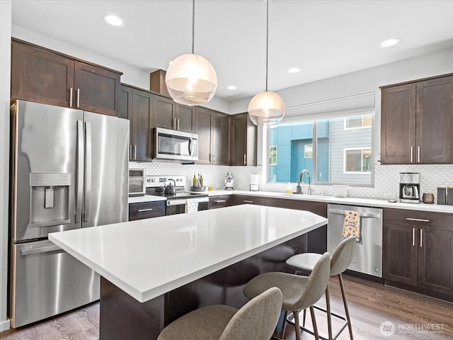 kitchen with a breakfast bar, stainless steel appliances, dark wood-type flooring, a sink, and dark brown cabinets