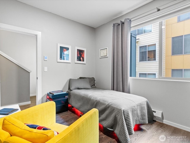 bedroom featuring a baseboard radiator, baseboards, and wood finished floors