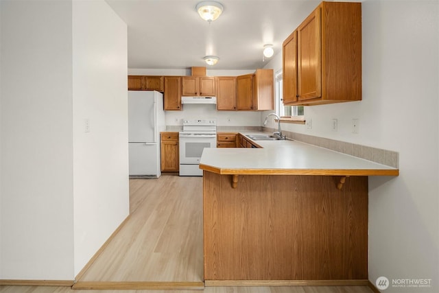 3802 Carpenter St, Mount Vernon, WA 98274 - kitchen featuring white appliances, under cabinet range hood, brown cabinets, light countertops, and a peninsula