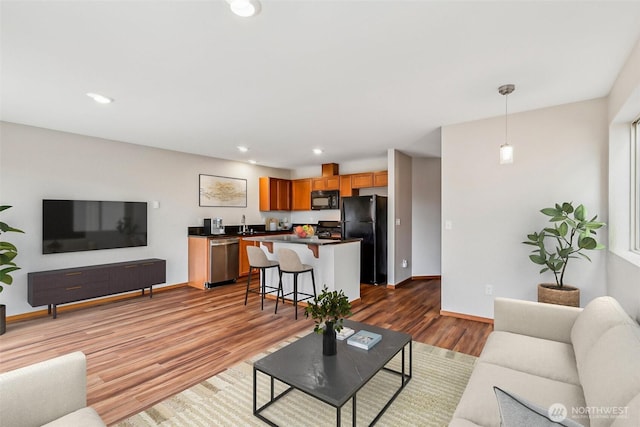 living area featuring recessed lighting, wood finished floors, and baseboards