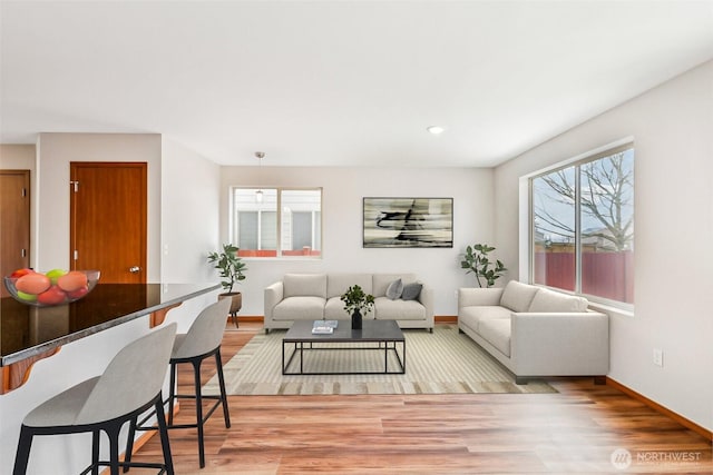 living area featuring baseboards and light wood-type flooring