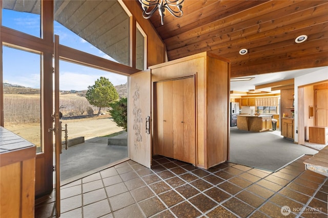 entryway with a notable chandelier, wooden ceiling, lofted ceiling, and dark tile patterned flooring