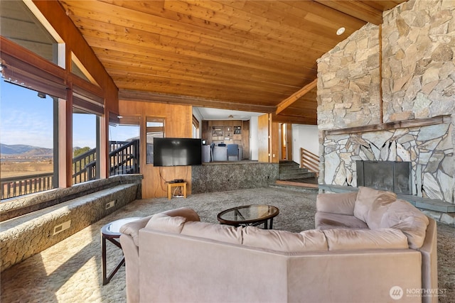 living area featuring wooden ceiling, lofted ceiling, and an outdoor stone fireplace