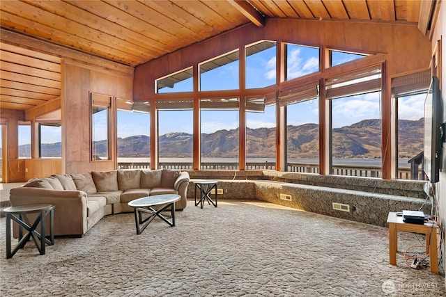 living area featuring a mountain view, carpet floors, and wooden ceiling