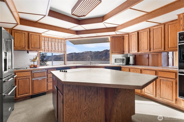 kitchen featuring appliances with stainless steel finishes, a center island, light countertops, and a sink