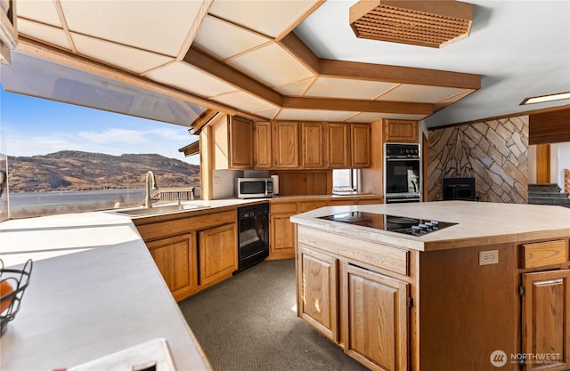 kitchen featuring a center island, light countertops, a mountain view, black appliances, and a sink