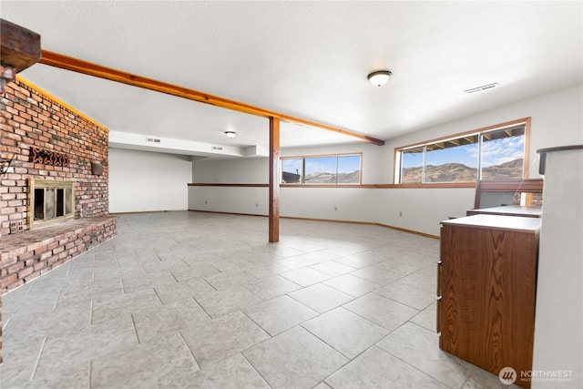 unfurnished living room featuring visible vents, a brick fireplace, baseboards, light tile patterned floors, and a textured ceiling