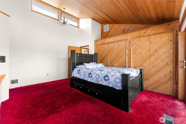 bedroom with visible vents, a notable chandelier, carpet, wood walls, and wooden ceiling