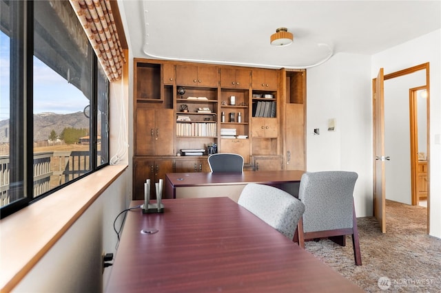 carpeted office space with a mountain view and built in desk