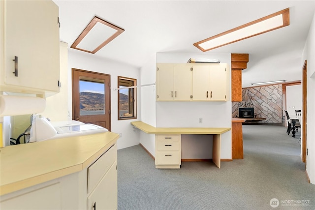 kitchen with light carpet, cream cabinets, light countertops, and washing machine and clothes dryer