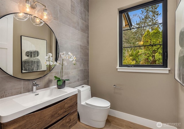 bathroom with toilet, tile walls, vanity, baseboards, and decorative backsplash