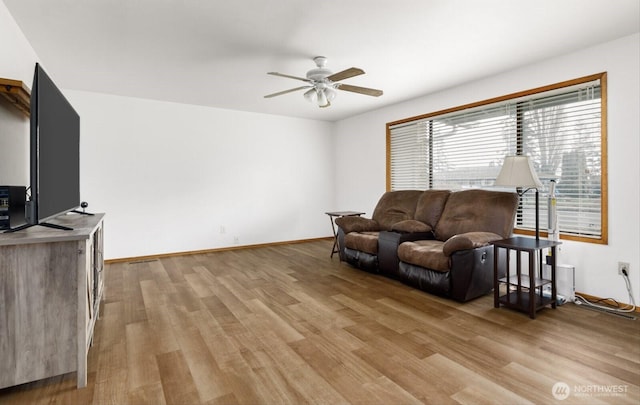 living area featuring light wood finished floors, a ceiling fan, and baseboards