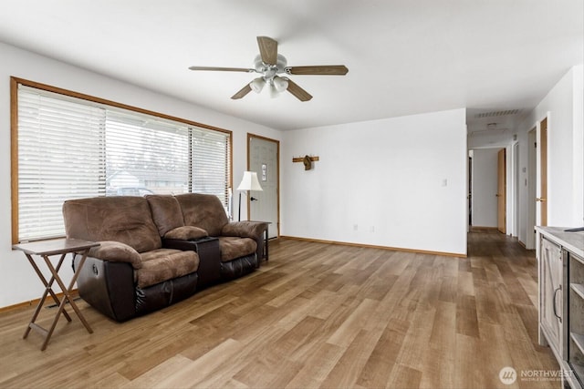 living room featuring light wood-style floors, baseboards, and a ceiling fan