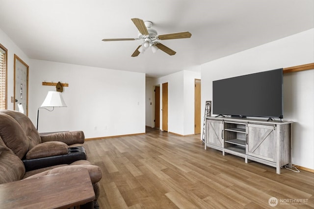 living area with a ceiling fan, baseboards, and wood finished floors