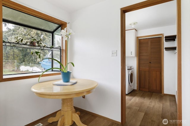 interior space featuring baseboards, washer and dryer, and wood finished floors