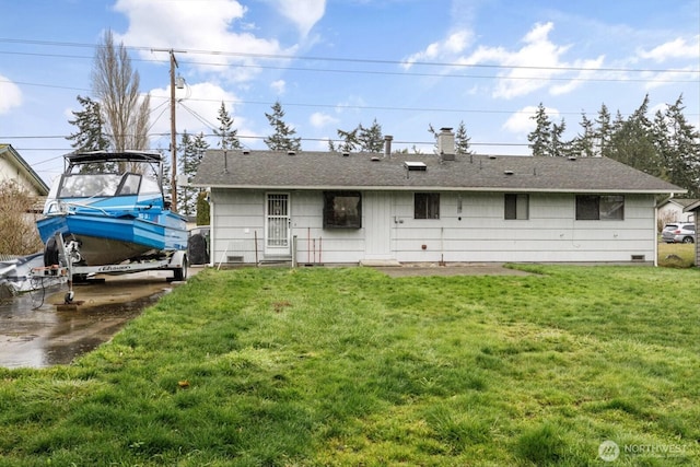 rear view of property with a shingled roof, a yard, and a chimney