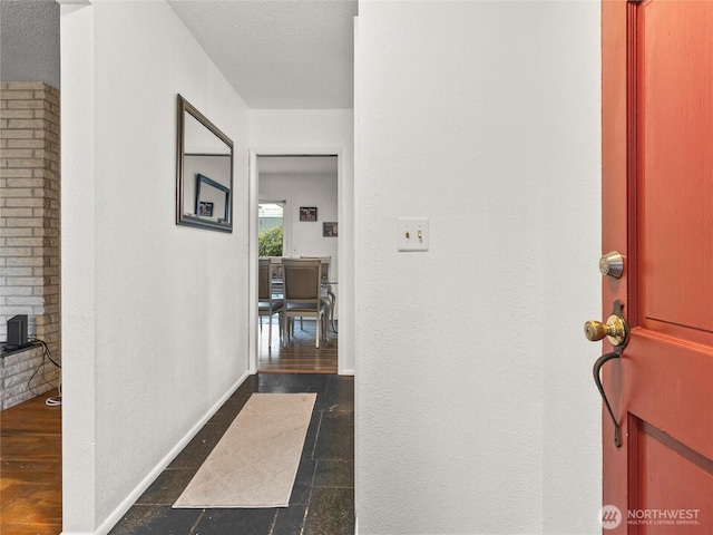 hallway with a textured ceiling and baseboards