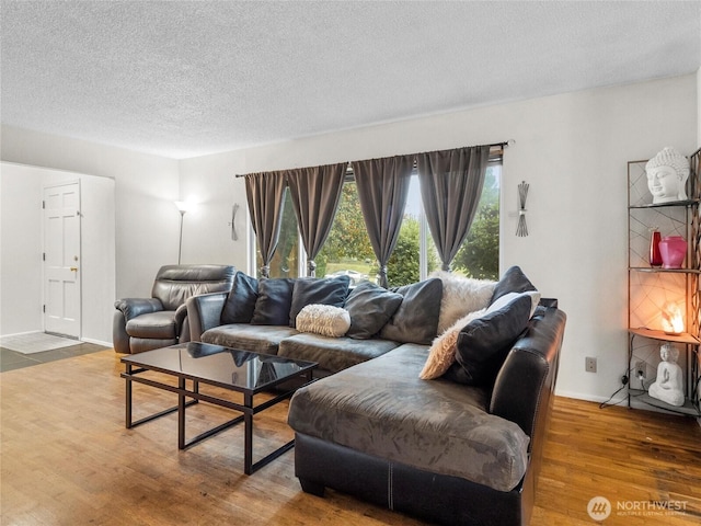 living room with a textured ceiling, wood finished floors, and baseboards