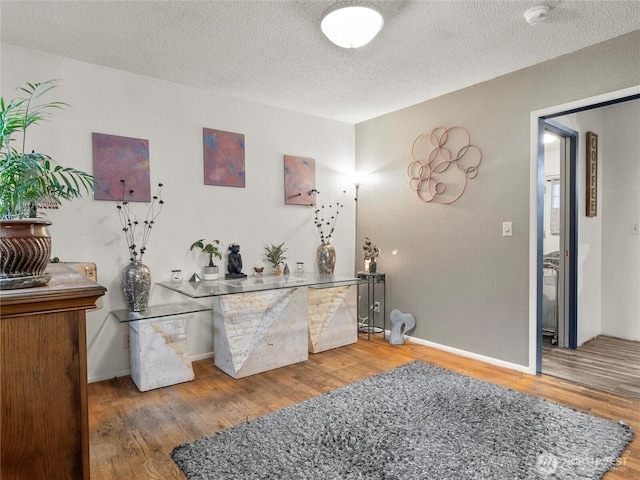 interior space featuring a textured ceiling, baseboards, and wood finished floors