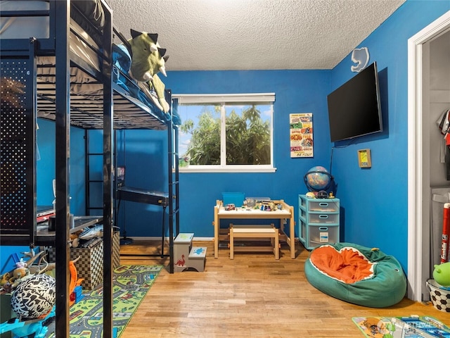 bedroom with a textured ceiling and wood finished floors