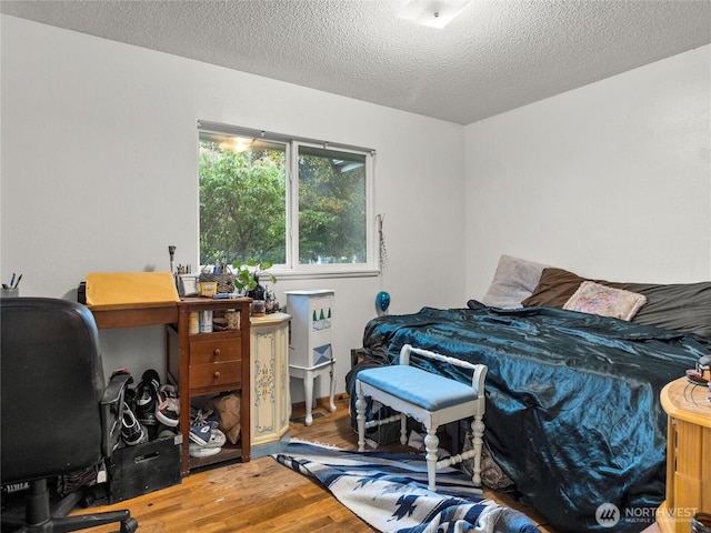 bedroom with a textured ceiling and wood finished floors