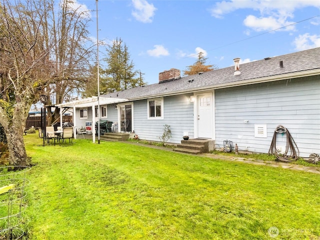 rear view of property with a shingled roof, a chimney, fence, and a yard