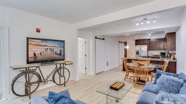 living room featuring light wood-type flooring, a barn door, a toaster, and baseboards