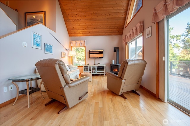 living area featuring a wood stove, light wood-style floors, and high vaulted ceiling