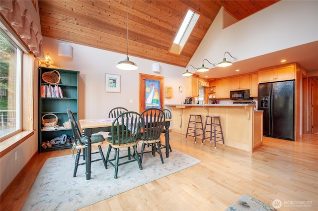 dining space featuring high vaulted ceiling, a skylight, wood ceiling, and light wood-style flooring