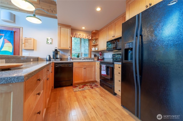 kitchen featuring light wood-style floors, light brown cabinets, a sink, and black appliances