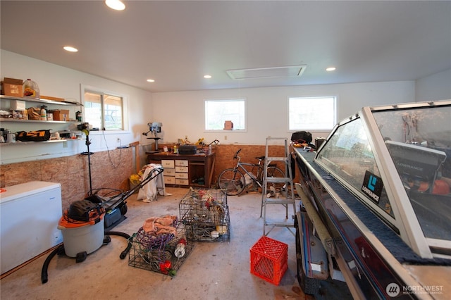 miscellaneous room with a healthy amount of sunlight, attic access, concrete flooring, and recessed lighting