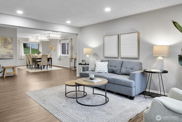 living room with recessed lighting, a textured ceiling, baseboards, and wood finished floors