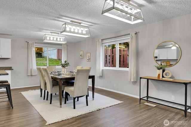 dining area featuring dark wood-style flooring, a textured ceiling, and baseboards