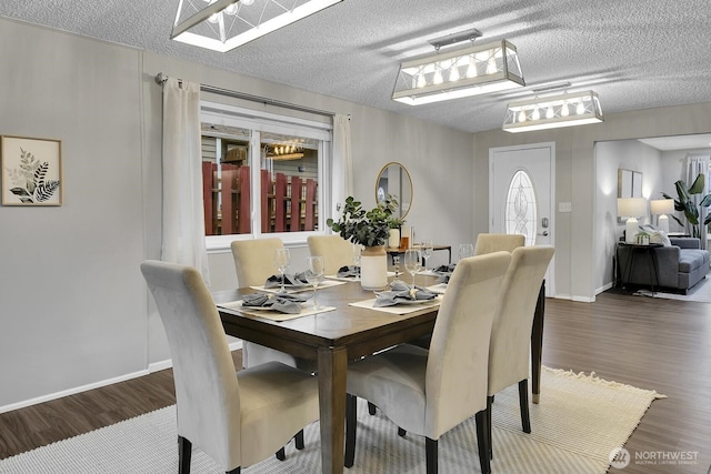 dining room with a textured ceiling, baseboards, and dark wood-type flooring