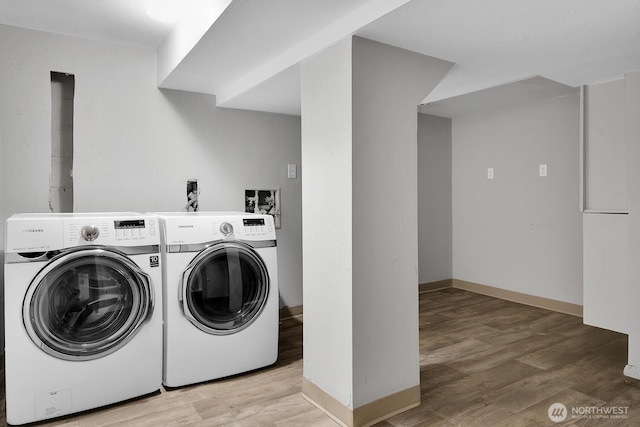 laundry area featuring baseboards, laundry area, light wood-style flooring, and washer and dryer