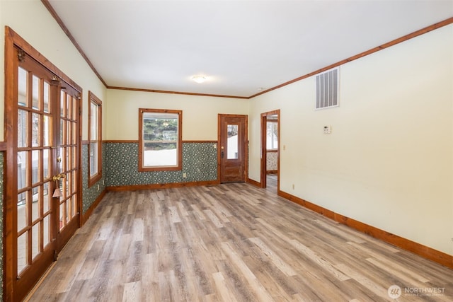 spare room featuring wallpapered walls, baseboards, visible vents, and wood finished floors