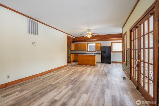 kitchen featuring light wood-style flooring, visible vents, open floor plan, black fridge, and brown cabinets