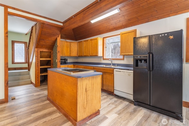 kitchen with dark countertops, a sink, a kitchen island, light wood-type flooring, and black appliances