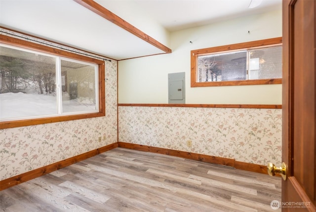 unfurnished room with wood finished floors, electric panel, baseboards, and wallpapered walls