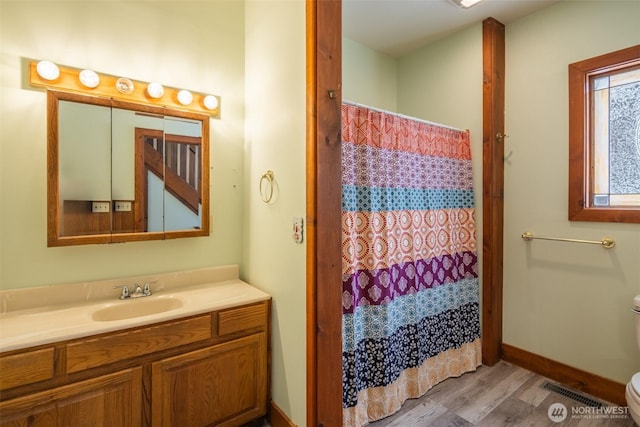 bathroom with baseboards, visible vents, toilet, wood finished floors, and vanity