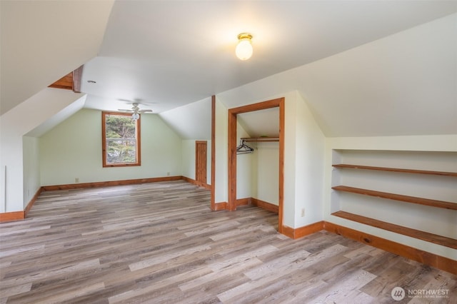 bonus room with baseboards, ceiling fan, wood finished floors, vaulted ceiling, and built in shelves