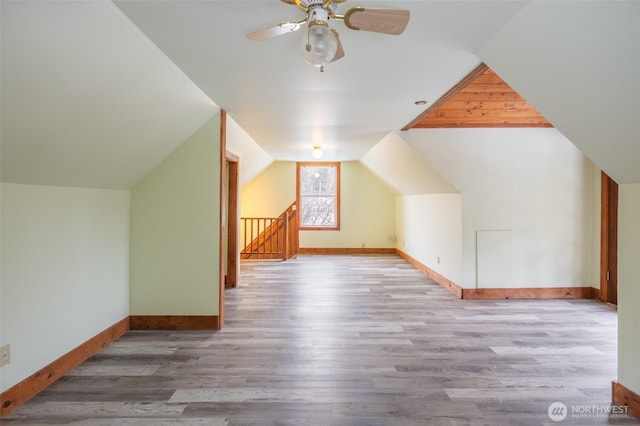 additional living space with a ceiling fan, baseboards, vaulted ceiling, and wood finished floors