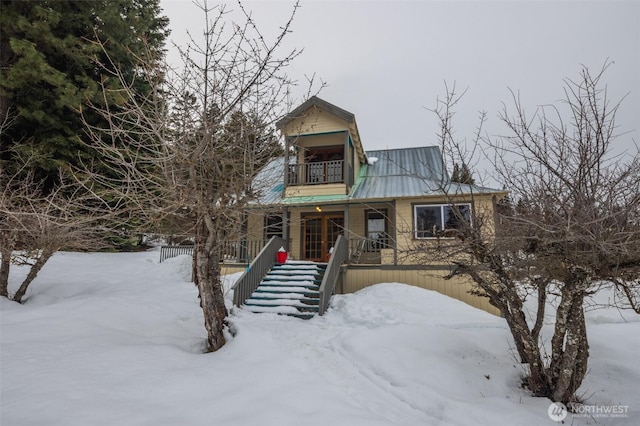 chalet / cabin with a balcony, stairs, metal roof, and a porch