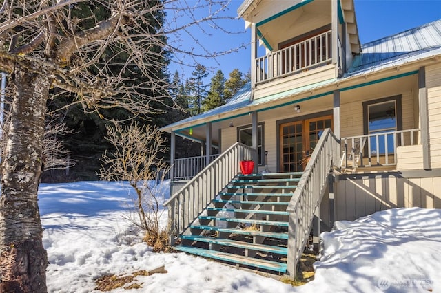 snow covered property entrance with a porch and metal roof