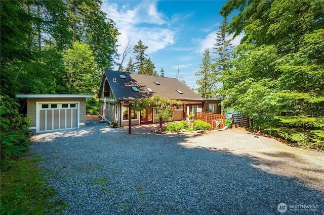 rustic home featuring a shingled roof, gravel driveway, and an outdoor structure