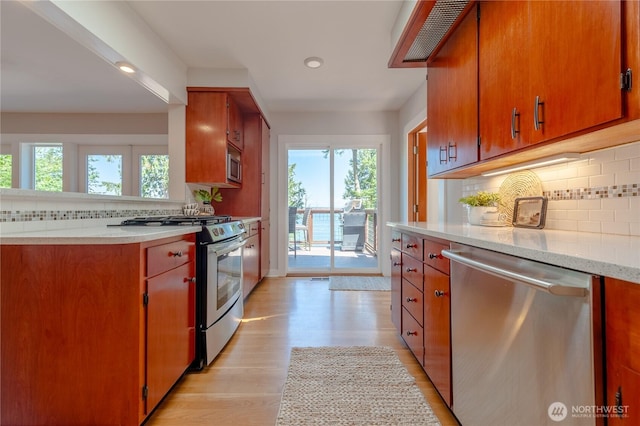 kitchen featuring light wood-style flooring, light countertops, appliances with stainless steel finishes, brown cabinets, and decorative backsplash