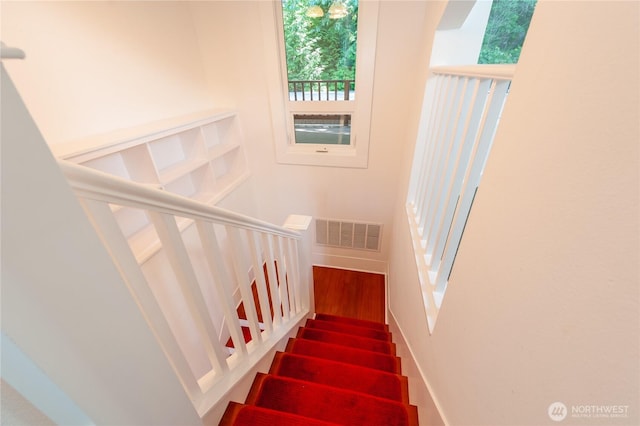 stairs with baseboards, visible vents, and wood finished floors