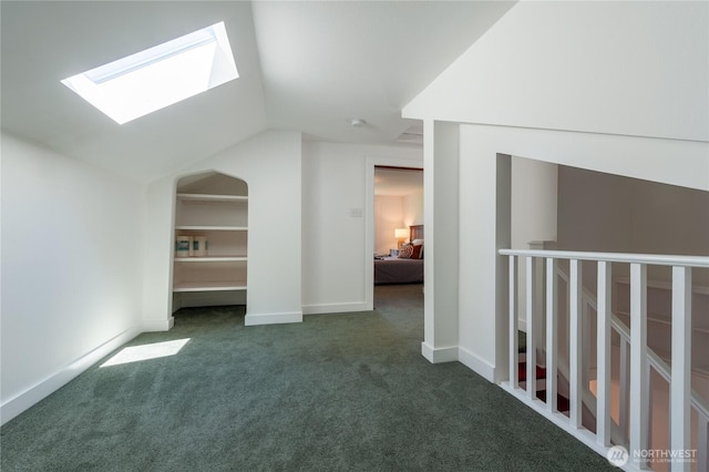 additional living space with vaulted ceiling with skylight, baseboards, and carpet flooring